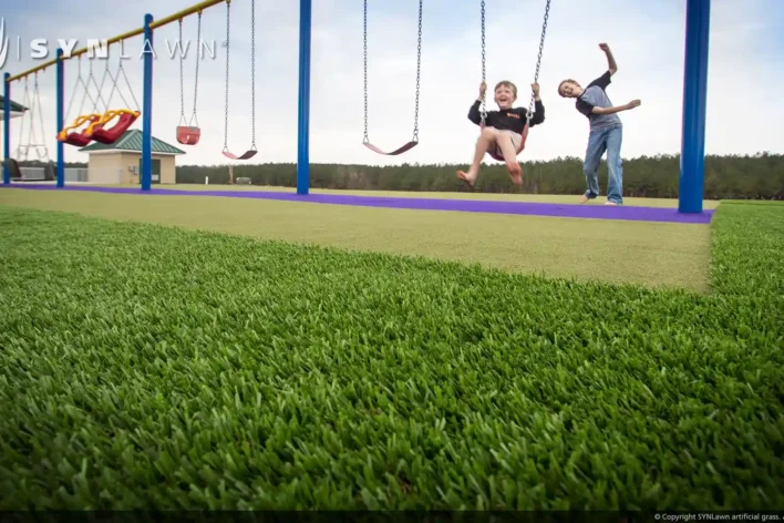 image of children on swing set over synthetic turf