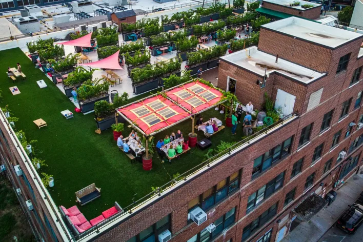 Rooftop winery in New York City featuring SYNLawn artificial turf lawn, dining pergola, and grapevine planters