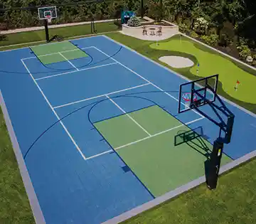 Backyard multi-sport court with basketball hoop, pickleball lines, and putting green